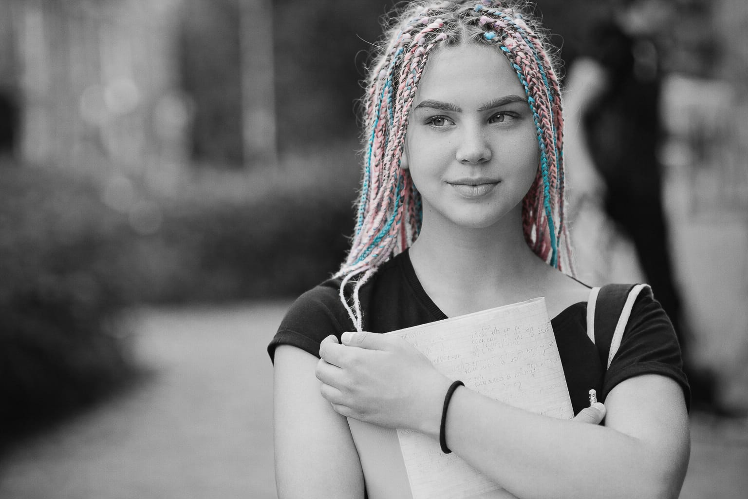 A girl with blue and pink braids holding a notebook